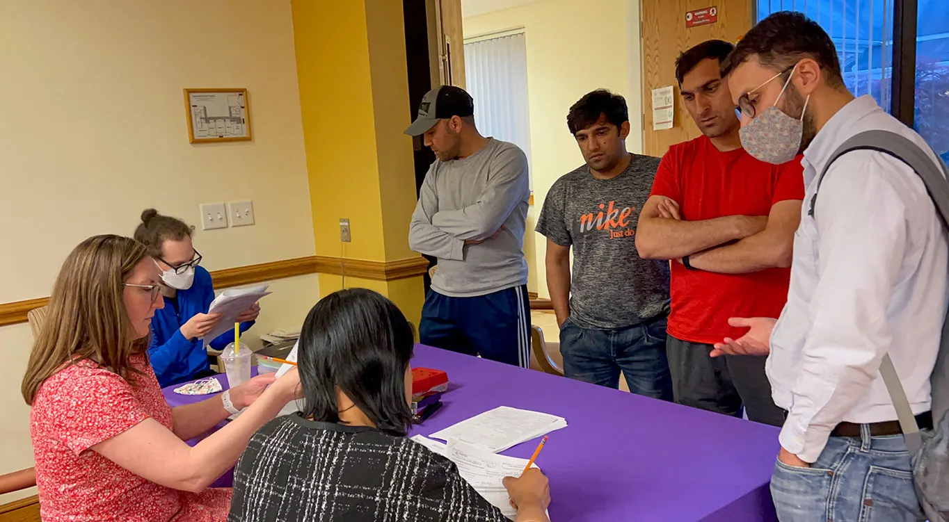Refugees submitting enrollment forms for english classes