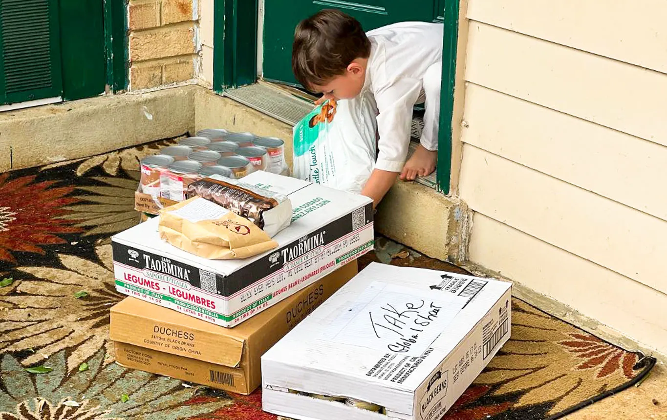 An Afghan kid carrying diaper and hygiene packages that were delivered to his apartment door