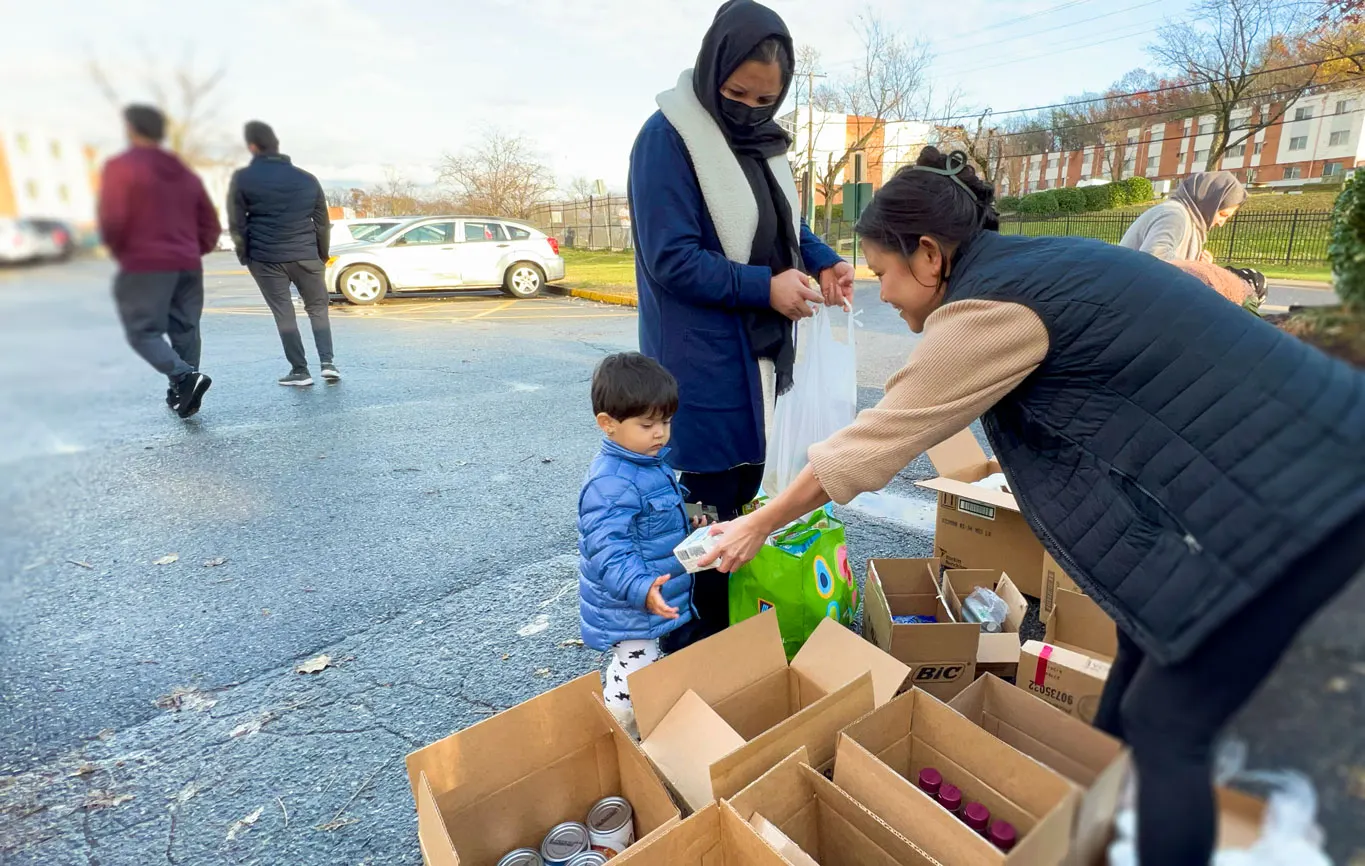 Volunteer handing out canned corn to a refugee child